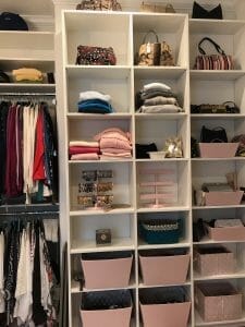 Custom-built closet with white shelving designed for handbags, folded clothes, and stylish pink storage bins