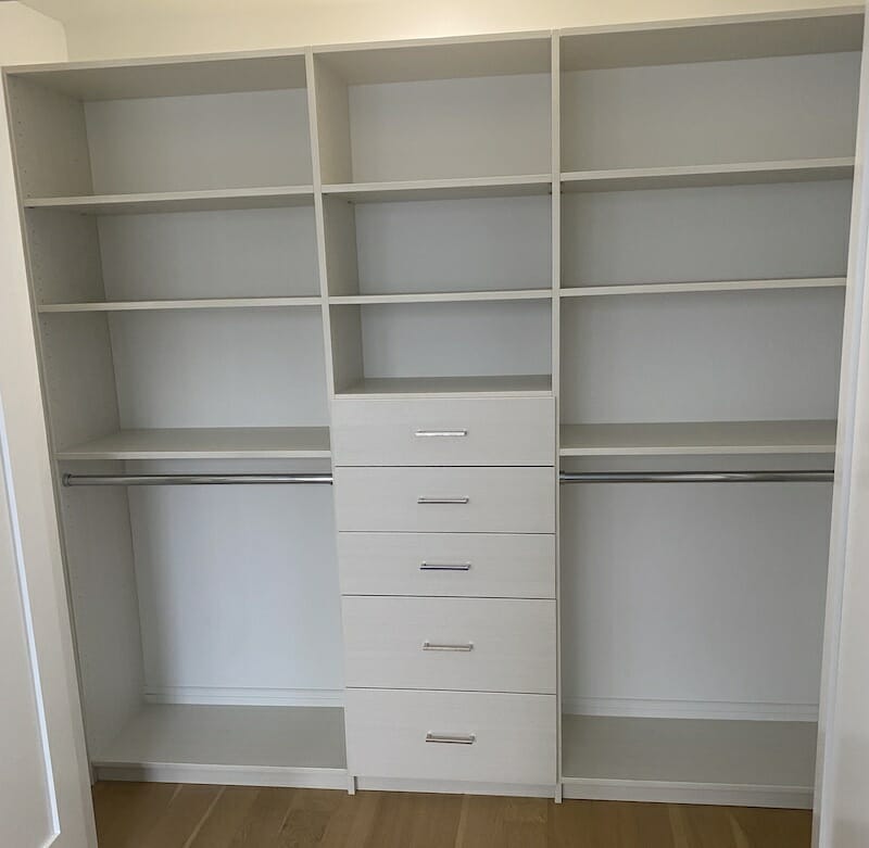 Contemporary white custom closet with built-in drawers, upper shelving, and double hanging rods for efficient storage
