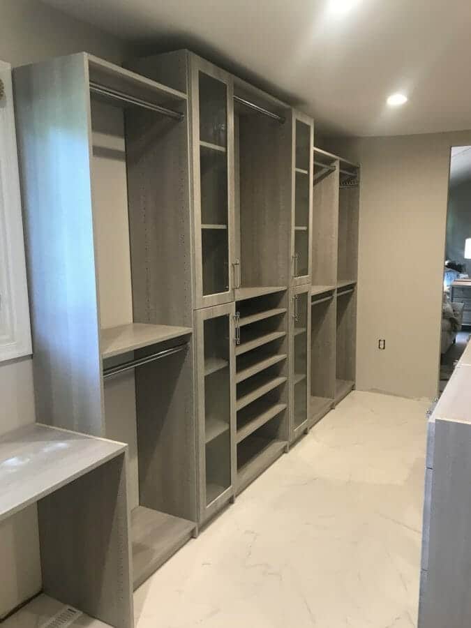 Contemporary gray custom closet featuring glass cabinet doors, hanging rods, and adjustable shelves for versatile organization