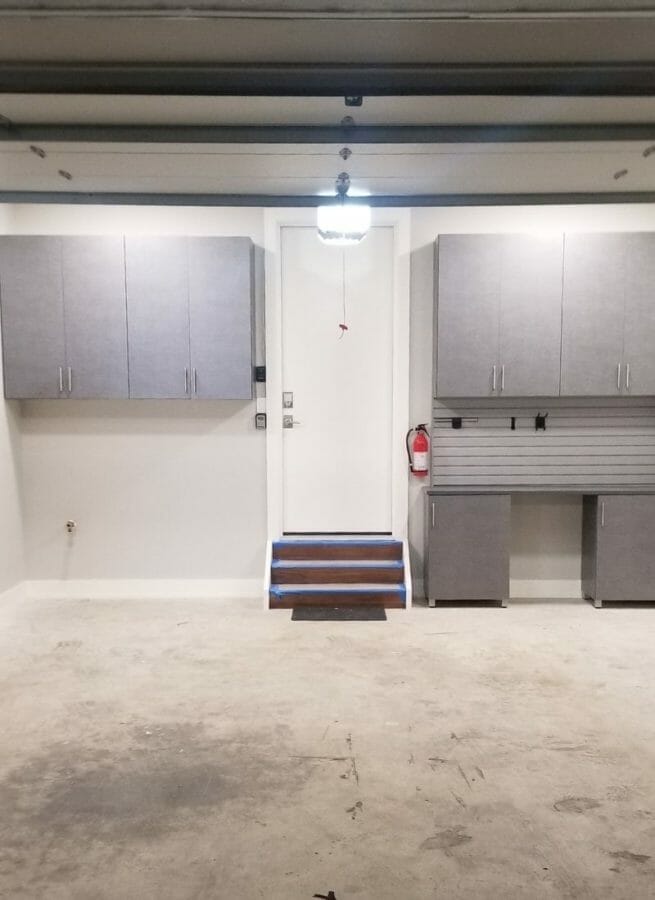 Organized garage interior with gray cabinets, overhead lighting, and clean concrete flooring for storage efficiency.