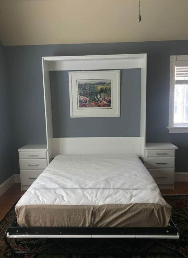 Open Murphy bed with mattress and wall frame, transforming from cabinet to functional guest sleeping area.