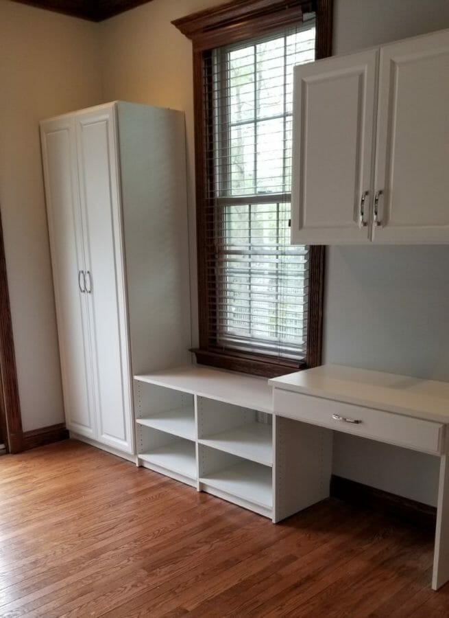 Bright office space with white cabinetry, desk, and shelving units for a clean and modern work environment.