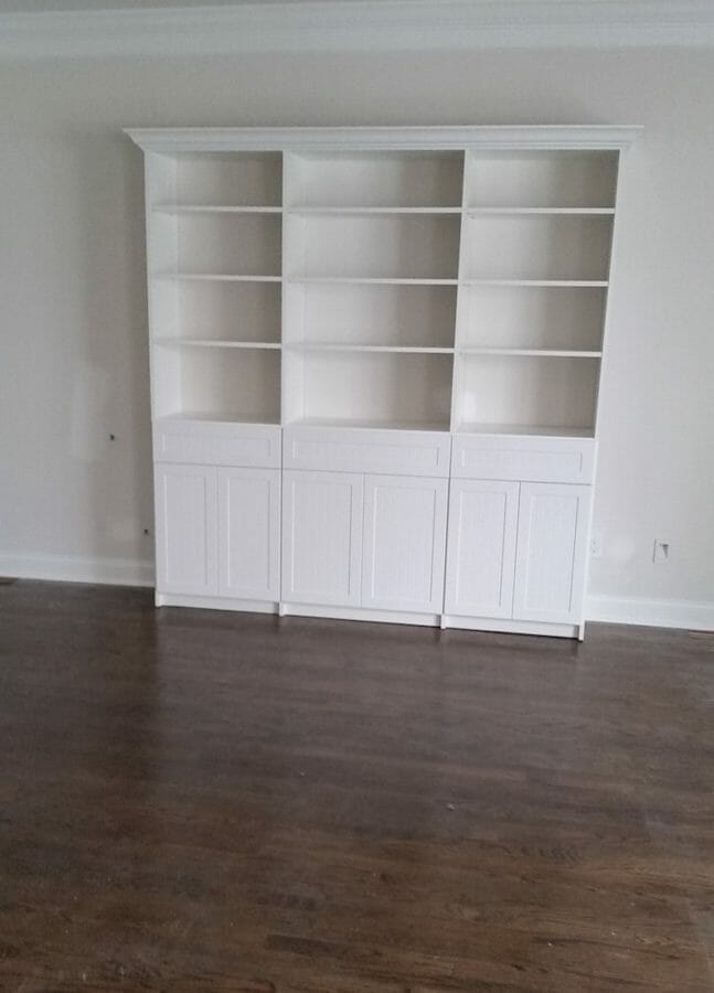 Custom white built-in shelving unit with lower cabinets and open display shelves for home organization and decor.