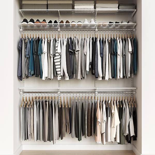 A well-organized closet with two rows of hanging clothes, including shirts, blouses, and pants in neutral colors. The top shelf holds neatly arranged shoes and storage boxes.